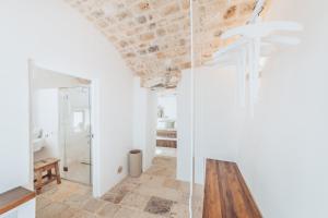 baño con ducha de cristal y mesa de madera en Borgo Canonica, en Cisternino