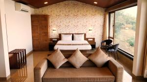 a bedroom with a bed and a couch in a room at Miraya Hotel in Panchgani