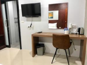 a desk with a television and a chair in a room at Easy Loft Hostel in Phuket