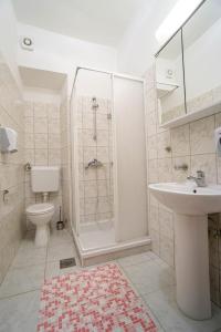 La salle de bains est pourvue d'une douche, d'un lavabo et de toilettes. dans l'établissement Apartments Titonel, à Savudrija