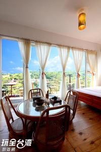 a room with a table and chairs and a bed at Museum Traveler's BnB in Sanzhi
