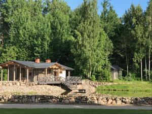 a log cabin by the water with a stone wall at Dzirnavas Pirtsmāja in Cesvaine