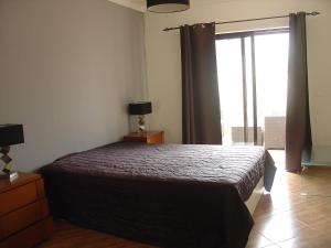 um quarto com uma cama e uma grande janela em Apartamento Sol e Mar 2 em Monte Gordo