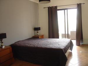 Un dormitorio con una cama y una ventana grande. en Apartamento Sol e Mar 2, en Monte Gordo