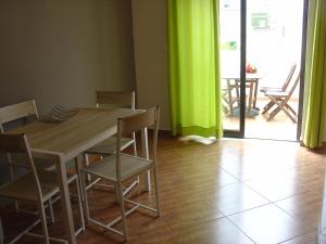uma mesa de jantar com cadeiras e uma cortina verde em Apartamento Sol e Mar 2 em Monte Gordo