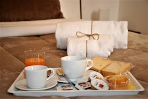 a tray with two cups and sandwiches and drinks on a couch at Casa vacanze Ai Corrieri in Palermo