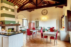 Il Mastio di Spedaletto في بينزا: مطبخ وغرفة طعام مع طاولات وكراسي حمراء