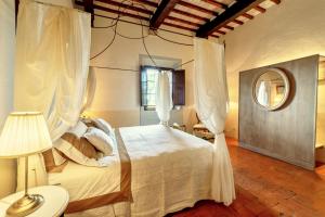 a bedroom with a white bed and a mirror at Il Mastio di Spedaletto in Pienza