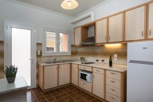 a kitchen with wooden cabinets and a white refrigerator at Georgia's Apartments, Ipsos - Complex S in Ipsos