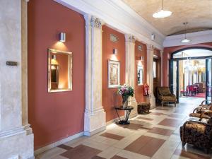 a lobby with red walls and a vase of flowers at EA Embassy Prague Hotel in Prague