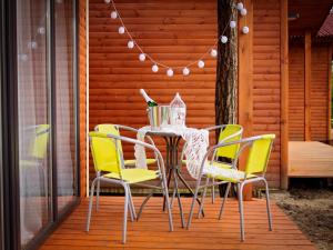 einen Tisch mit gelben Stühlen auf einer Veranda in der Unterkunft Ośrodek Delfin in Ślesin