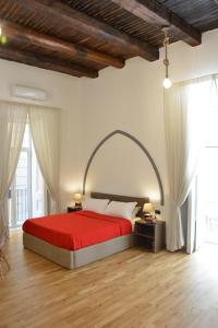 una camera con letto rosso in una stanza con finestre di Domus Studio 25 bed & breakfast a Napoli