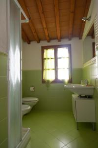 Baño verde con 2 lavabos y ventana en Pepe Nero by HelloElba, en Portoferraio