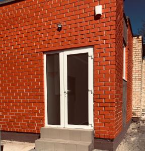 un edificio de ladrillo rojo con una puerta blanca. en Romeo VIP apartamentai en Panevėžys