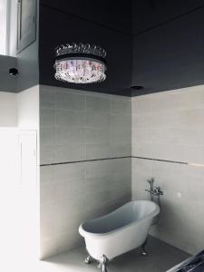 a bath tub in a bathroom with a chandelier at Romeo VIP apartamentai in Panevėžys