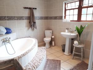 a bathroom with a tub and a toilet and a sink at Knysna N2 Lodge in Knysna +68 photos