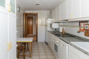 a kitchen with white cabinets and a sink and a table at Nueva Vista 2º-4 in Cullera