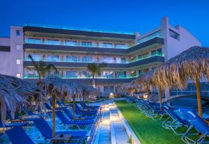 a hotel with chairs and umbrellas and a pool at Infinity Blue Boutique Hotel & Spa - Adults Only in Hersonissos