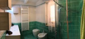 a green tiled bathroom with a toilet and a sink at Residence Baia Infreschi in Marina di Camerota