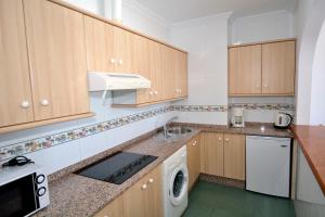 a kitchen with wooden cabinets and a washer and dryer at Apartamentos HC Burriana Playa in Nerja