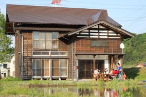 a group of people sitting at a table in front of a house at KOME HOME in Tokamachi