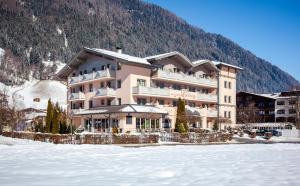 a large building with snow in front of a mountain at Hotel & Appartements Alpenresidenz Viktoria inklusive Sommer Stubai Super Card in Neustift im Stubaital