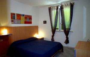 a bedroom with a blue bed and a window at Etruriamare in San Vincenzo