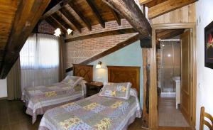 a bedroom with two beds and a brick wall at Casa Paulino in Los Corrales de Buelna