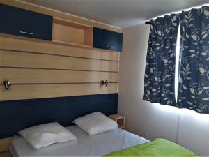 een slaapkamer met een bed en een blauw hoofdeinde bij Camping de Retourtour in Lamastre +124 foto's