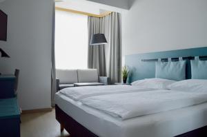 a bedroom with a large white bed and a chair at Pension Elisabeth - Rooms & Apartments in Salzburg