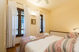 two beds in a room with two windows at Anastasia's Venetian House in Rethymno