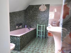 a bathroom with a pink tub and a sink at Le Mans Chambre in Le Mans