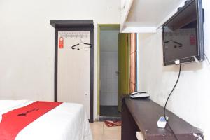 1 dormitorio con 1 cama y TV de pantalla plana en RedDoorz near Universitas Muhammadiyah Makassar, en Makassar