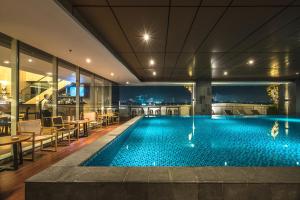 uma piscina num hotel com mesas e cadeiras em Oakwood Hotel & Residence Surabaya em Surabaya