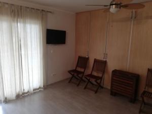- un salon avec deux chaises et une télévision à écran plat dans l'établissement Estudios Solmar Solo Familias Serviplaya, à Gandía