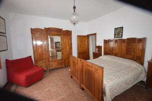 a bedroom with a bed and a red chair at Il cedro in Molino del Pallone