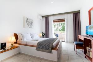 a bedroom with a bed and a desk and a television at Acrotel Elea Beach in Elia