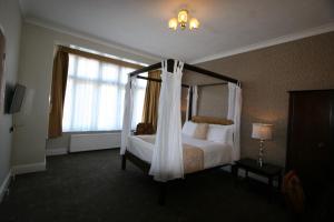 ein Schlafzimmer mit einem Himmelbett und einem Fenster in der Unterkunft Grange Moor Hotel in Maidstone