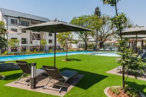 a patio with chairs and an umbrella next to a pool at Alimama Spaces: Vik Whisken in Midrand