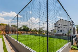 a tennis court behind a fence with a field of grass at Alimama Spaces: Vik Whisken in Midrand