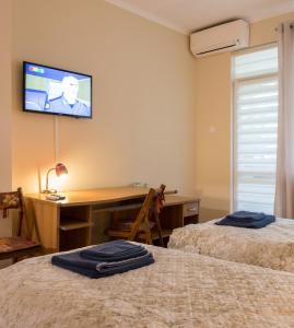1 dormitorio con 2 camas y escritorio con TV en la pared en Bright and Cozy 2BD. Flat in Plovdiv City Centre en Plovdiv