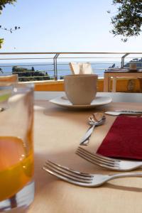 a table with fork and knife and a cup of juice at Taormina Panoramic Hotel in Taormina