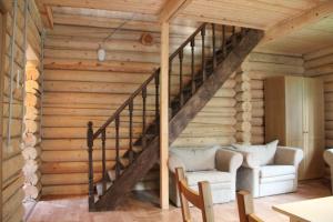 una escalera en una casa de madera con 2 sillas y un sofá en Velikoe Ozero - Valday, en Simanikha