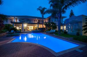 a swimming pool in front of a house at night at Fifth Avenue Beach House in Port Elizabeth