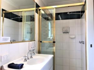 a bathroom with a shower, sink, and mirror at Airport Clayfield Motel in Brisbane