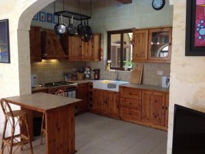 a kitchen with wooden cabinets and a sink and a table at Carpe Diem in Xagħra