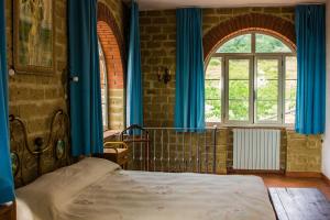 a bedroom with a bed with blue curtains and a window at Podere Le Chiuse in Sovana