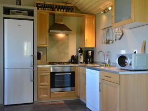 a kitchen with wooden cabinets and a white refrigerator at Spacious Chalet in Vielsalm with Garden in Vielsalm