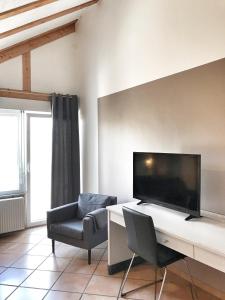 a living room with a desk with a tv and a chair at Aparthotel Wettenberg in Gießen