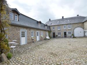 ウェームにあるMedieval farmhouse with private garden in Waimes near the lakeの白いドアと中庭のある大きなレンガ造りの建物